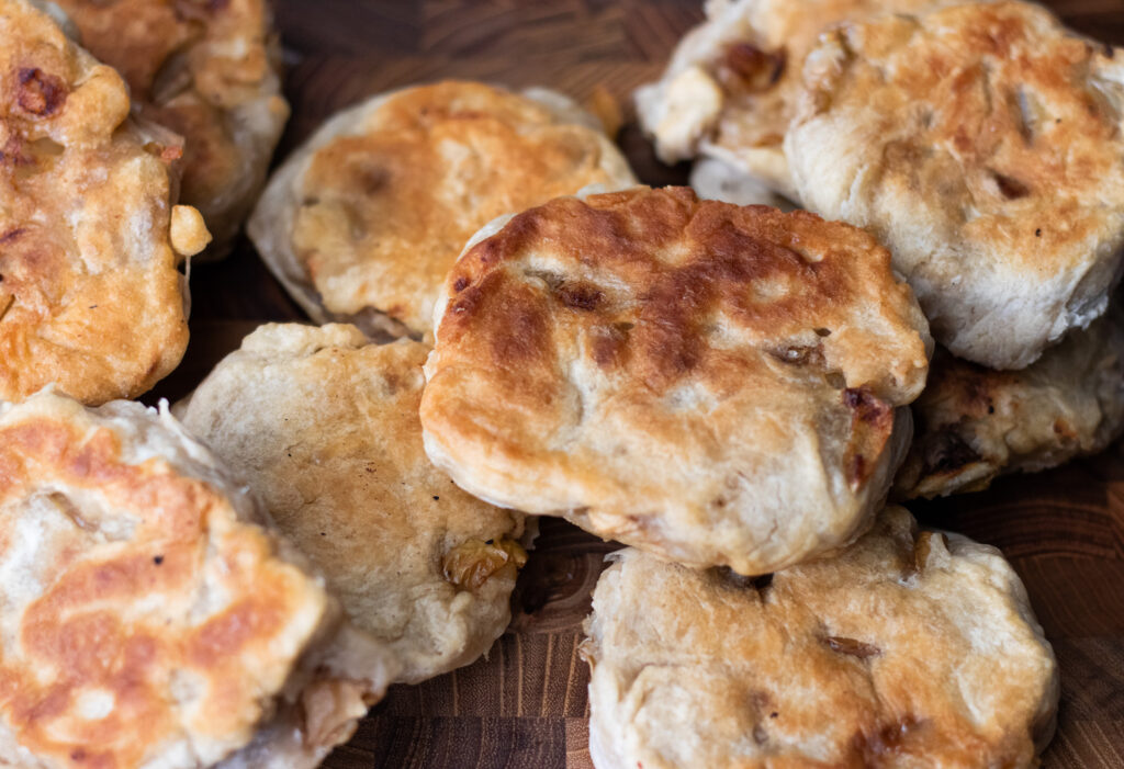 Several sourdough English muffins with apple on wooden board.