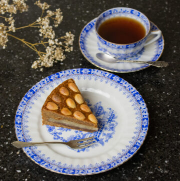 piece of spiced cake filled with almond paste on saucer and a cup of tea