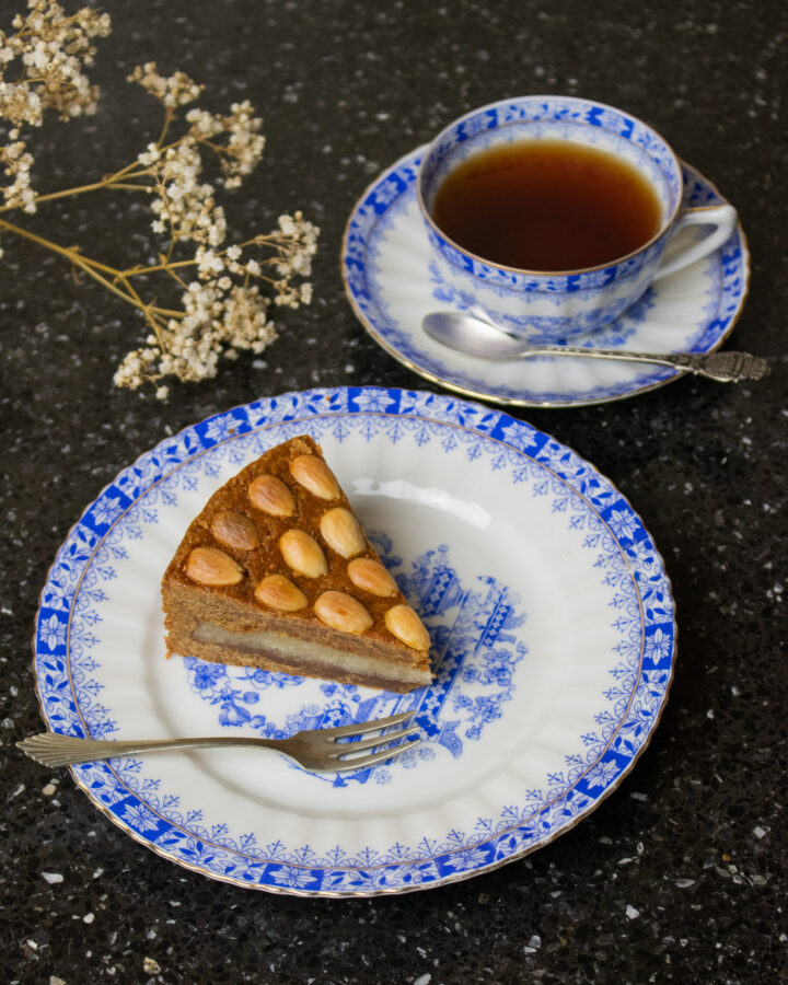 piece of spiced cake filled with almond paste on saucer and a cup of tea